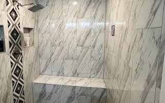 Tiled walk-in shower with a marble-look wall, built-in niche, glass panel and a full-width bench